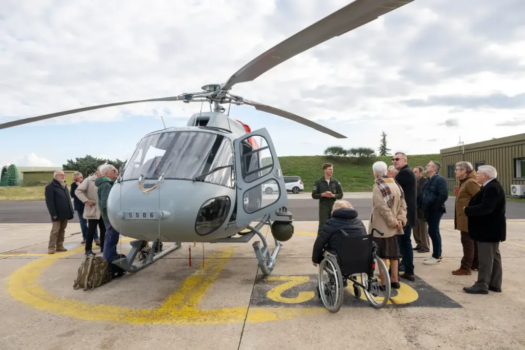 Les membres du conseil autour d'un hélicoptère sur l'aire de stationnement
