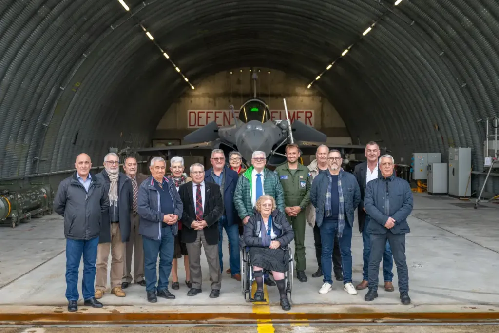 Photo de groupe du conseil devant un Rafale, dans un abri